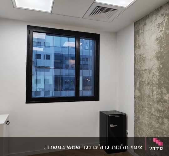 מקרר קטן שחור ליד קיר בטון חשוף